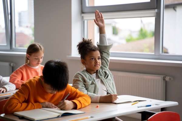 A child raising her hand with a question as they learn comprehension.