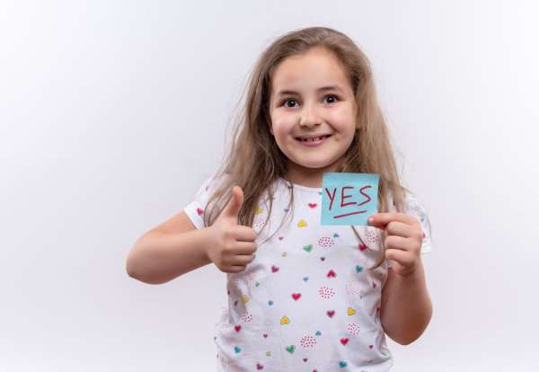 A child holding a flashcard with the word 'yes!' while giving a thumbs up, embodying the joy of mastering letter recognition