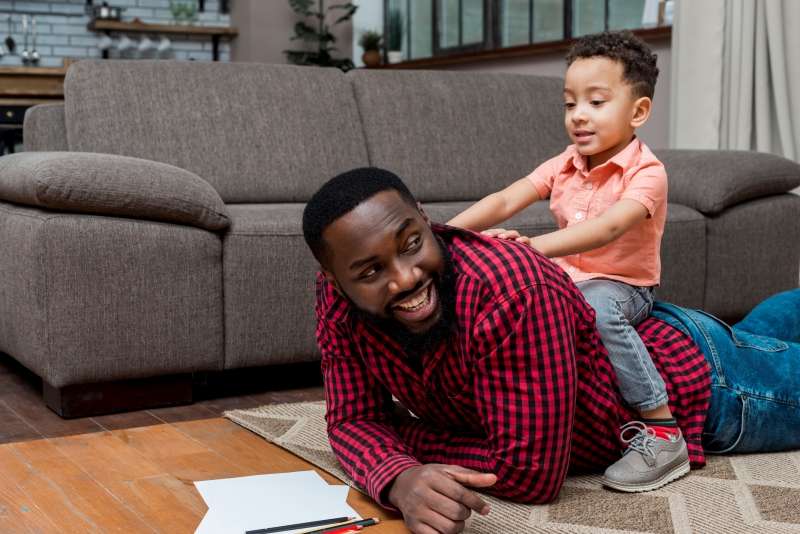  A joyful image of a child and his father playing and laughing together on the floor.  This shared happiness emphasizes the enjoyable aspect of reading. 