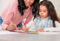 Mother helping her child with writing.