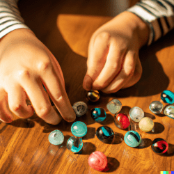 A close up shot of a child's hands sorting and counting marbles.