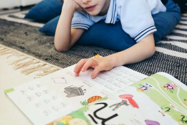 Young child tracing letters in a book.