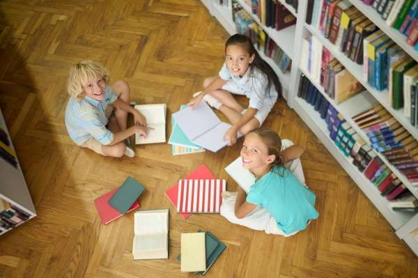 Family bookshelf with a variety of children's books. Children are enjoying.