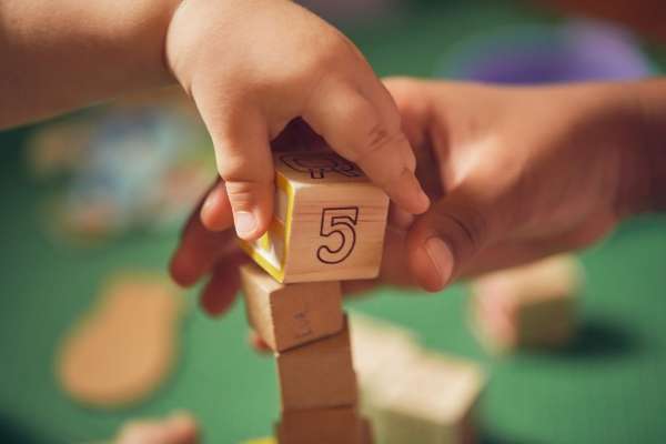 Close-up of hands placing number puzzle pieces.