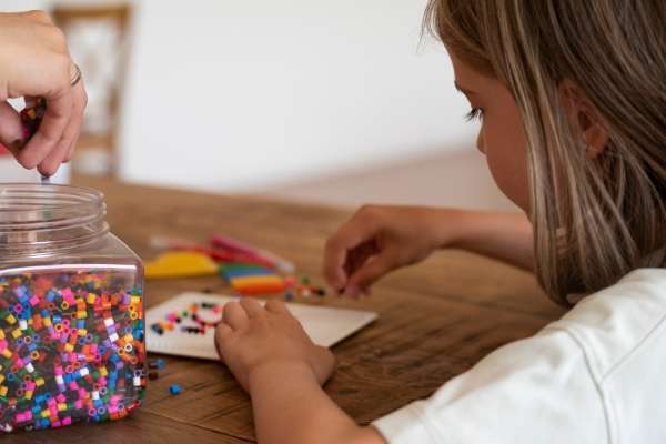 Child using colorful beads to learn math using different patterns.