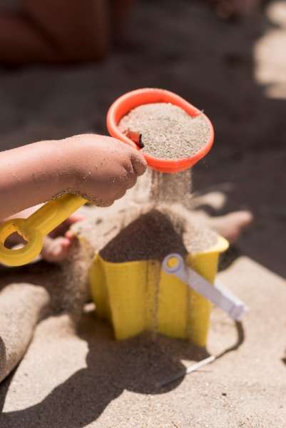 Child comparing sand volume in two containers.