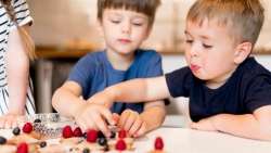 Children playing and counting berries during breakfast