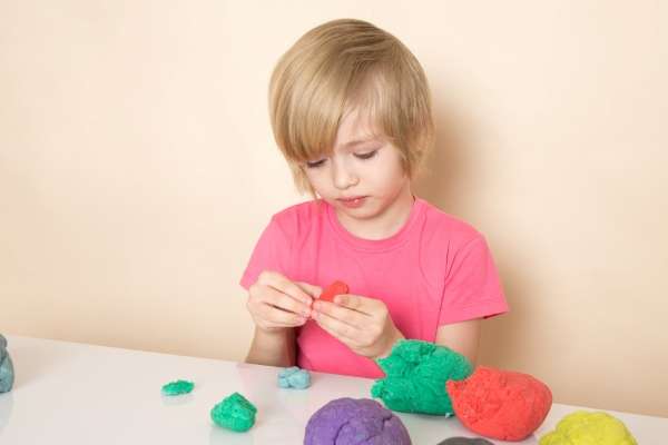 A preschooler crafting numbers with vibrant playdough.