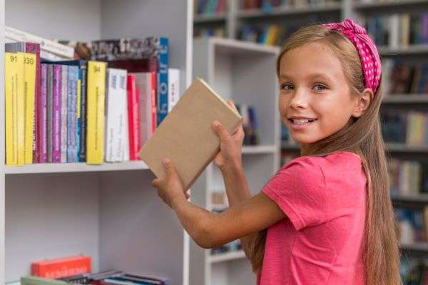 An image of gal in the library selecting a book to read.