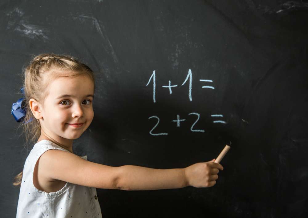 A child working on additional math on the black board.