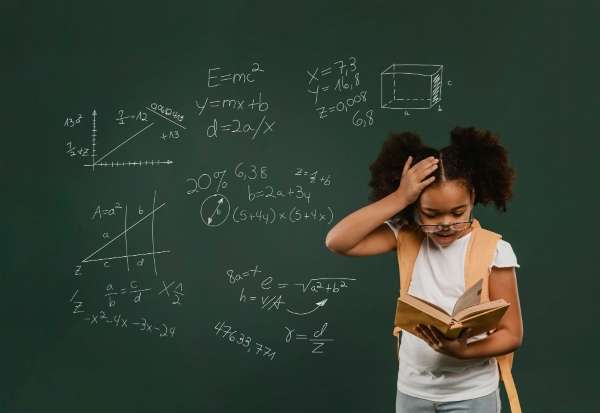 Girl solving math problem on a black board.