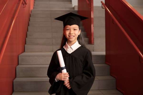 A preschooler during here graduation in a graduation gown.