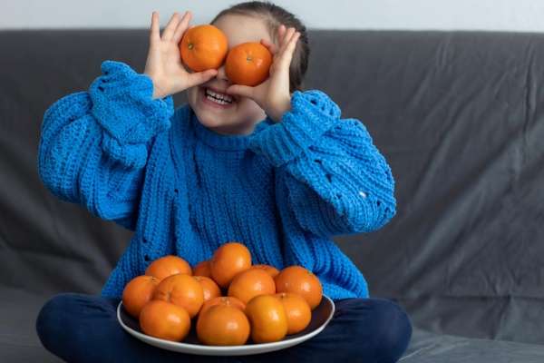 A child counting and playing with oranges.