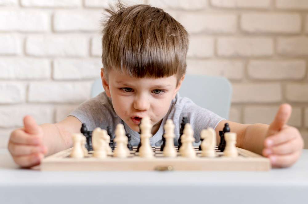 Excited children playing chess on a  table.