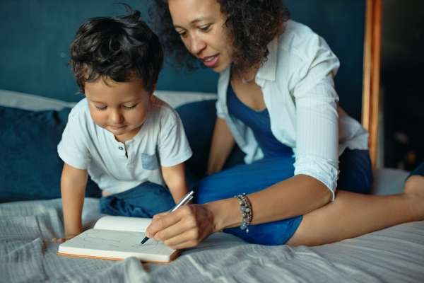 Mother helping child with writing.