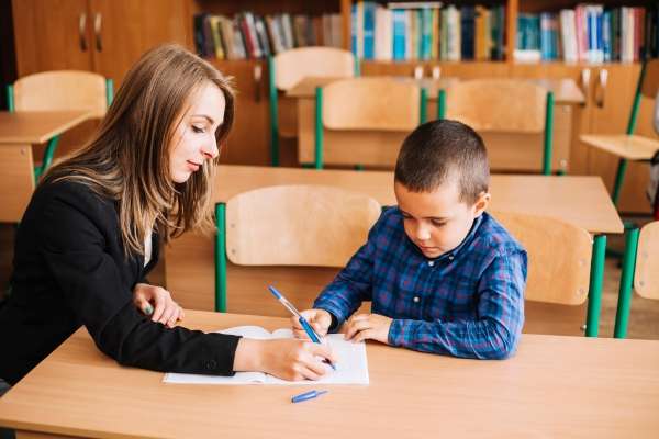 A tutor giving attention a child as she teaches him.