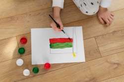 Child coloring a sequence of shapes on a worksheet.