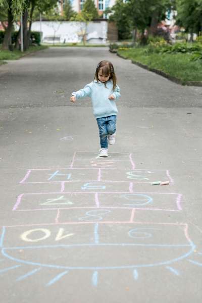 Child jumping in a hopscotch game with numbered squares