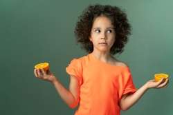 A child holding to half slices of an orange as a way of learning basic fractions concepts.