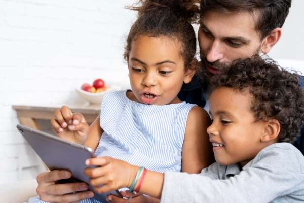 A parent teaching his preschoolers basic fractions concepts using an iPad