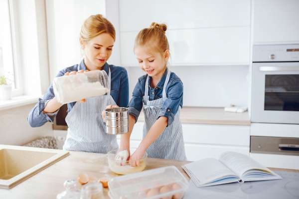 A child and parent measuring flour in the kitchen and baking together