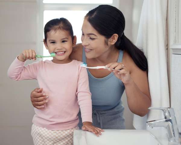 Mother and young child brushing teeth before bed.
