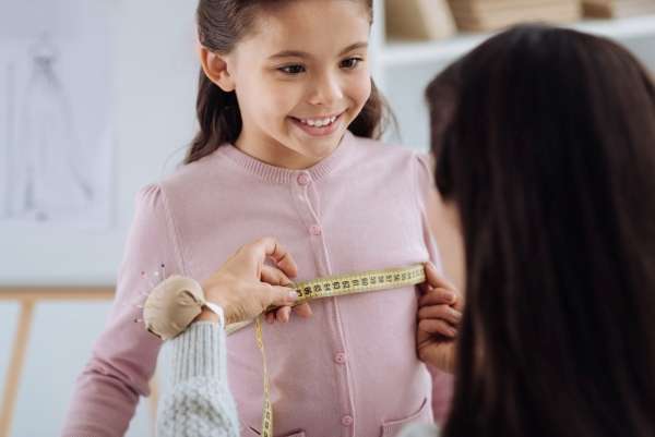 Mother and daughter playing with a tape measure.