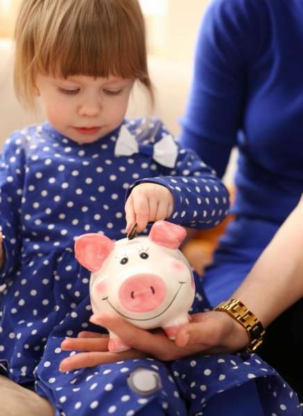 Child saving a coin in a piggy bank.