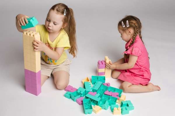 Children building and comparing two block towers.