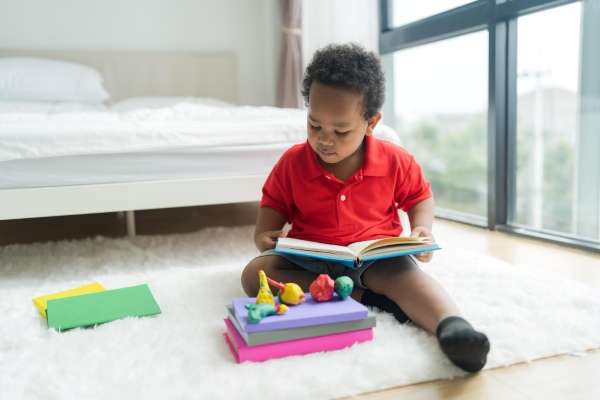 A young preschooler reading a book on the floor!