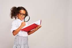 Young child analyzing vibrant data charts with a magnifying glass as she learns data collection and analysis