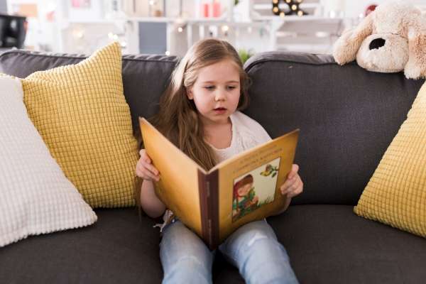 Preschooler engrossed in reading a colorful storybook.