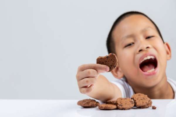 A young child eating cookies while counting them.