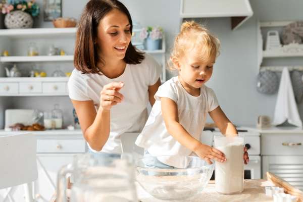 Child pouring flour while baking with the mother as a way to understand basic  measurement concepts.