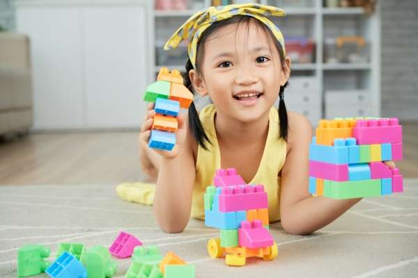 A child playing with toy blocks of different colors.