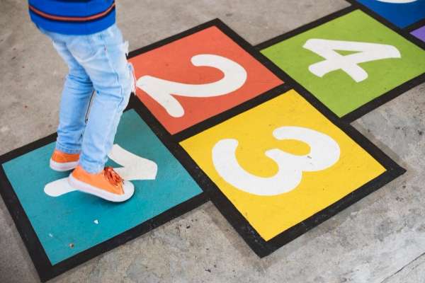 Child playing 'Number Jump' outdoors on a sunny day.