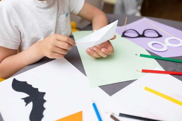 Child cutting pieces of origami papers and learning Simple Origami for Preschoolers: A Japanese Art of Paper Folding